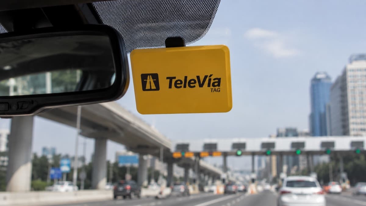 Dispositivo TAG TeleVía instalado en parabrisas con autopista mexicana al fondo