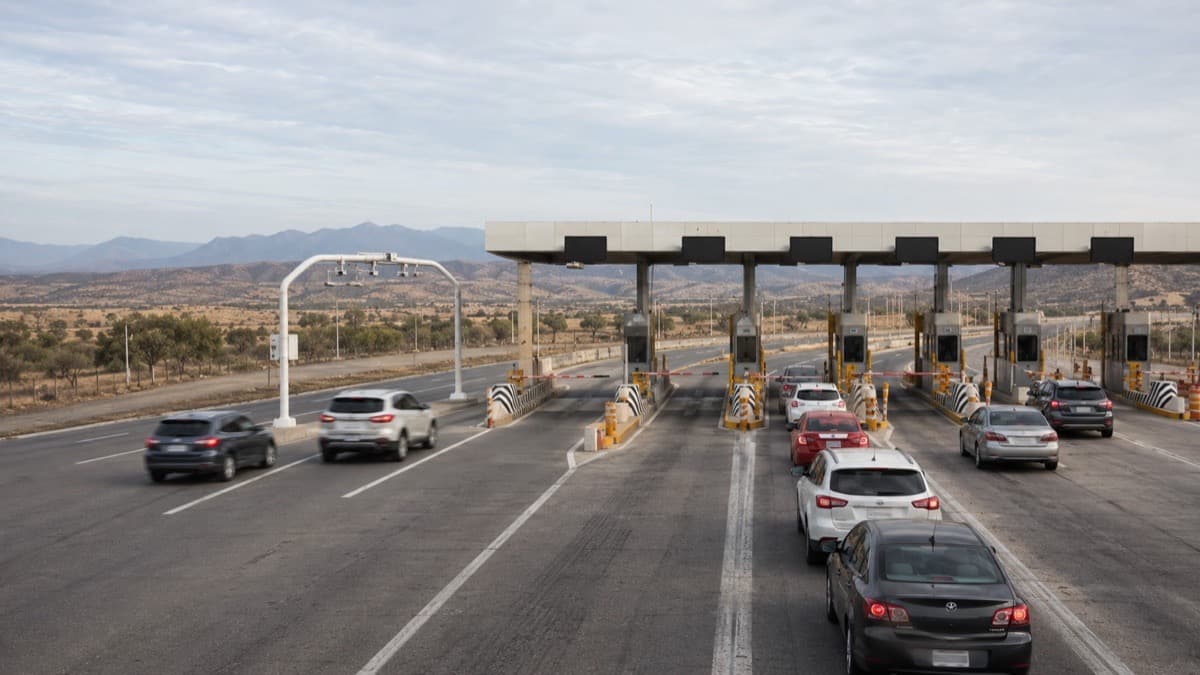 Fila de coches esperando en cabinas de cobro de una caseta mexicana con carril TAG separado
